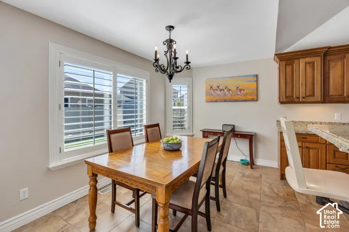 Tile flooring, white window shutters, wood-finish cabinetry, light-toned walls, and granite-style countertops