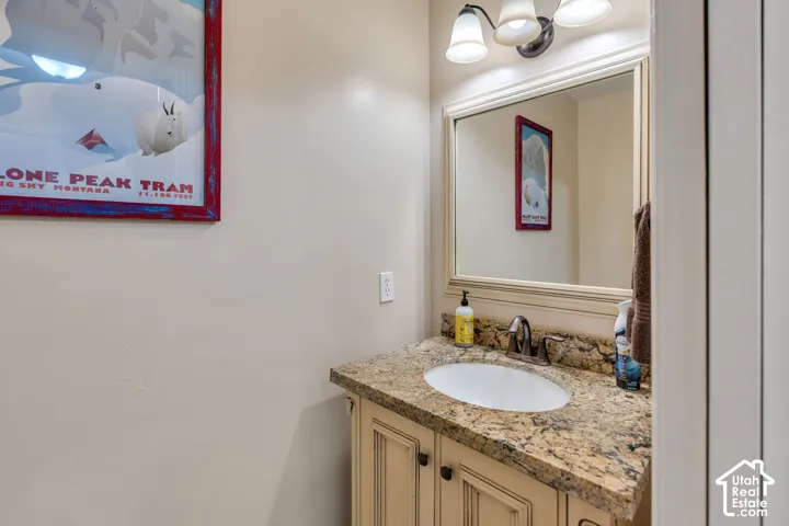 Vanity with stone-finish countertop, under-mount sink, and framed mirror