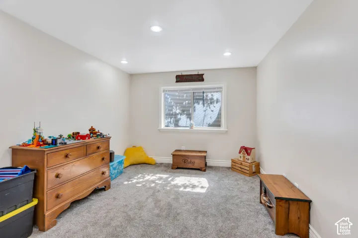Recessed ceiling lighting, light gray wall finish, window with white trim, and gray carpet flooring