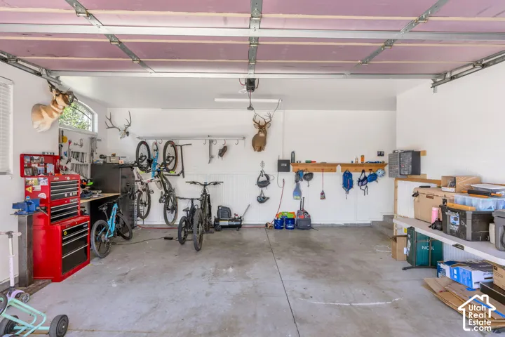 Attached garage featuring a concrete floor, built-in shelving, and a wall-mounted workbench