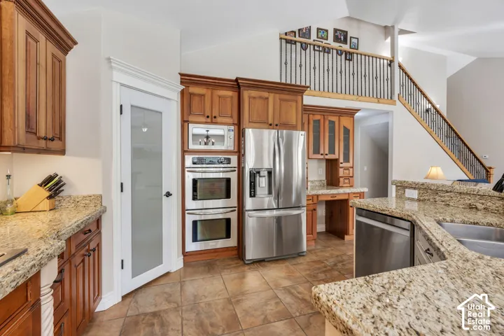Kitchen featuring wood cabinetry, granite countertops, stainless steel appliances, and tile flooring