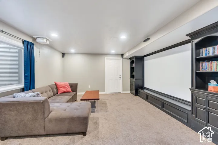 Recessed lighting, built-in shelving, white door, wall-mounted projection screen, and carpet flooring