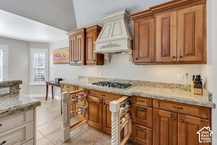 Kitchen featuring wood cabinetry, light-toned stone countertops, and a built-in gas range