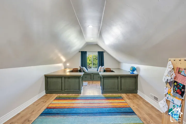 Bonus room above the garage. Sloped ceilings, wood-finish flooring, recessed lighting, built-in desks with beadboard paneling, and a built-in window bench