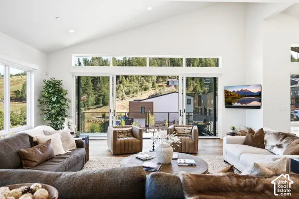 Vaulted ceiling with recessed lighting, large sliding glass doors, white walls, and wood-finish flooring. The photos are renderings only - these photos are for a similar unit in Discovery Ridge. Not this actual model.