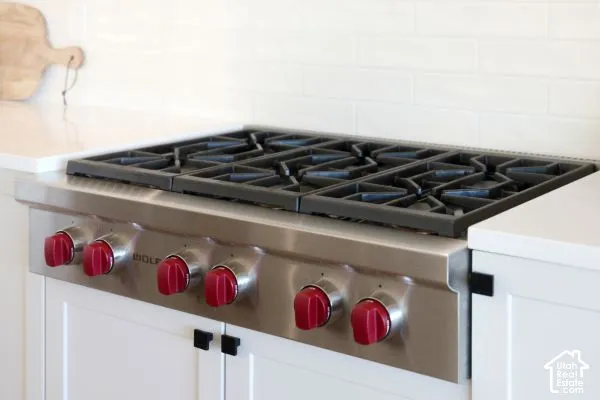 Professional-grade stainless steel range with red control knobs, set within white cabinetry and a light-colored countertop. The photos are renderings only - these photos are for a similar unit in Discovery Ridge. Not this actual model.
