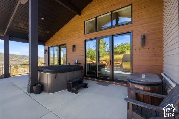 Covered patio featuring a hot tub, concrete flooring, exterior wood siding, and large sliding glass doors. The photos are renderings only - these photos are for a similar unit in Discovery Ridge. Not this actual model.