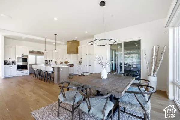 Open-concept kitchen and dining area featuring light wood-finish flooring, a kitchen island with seating, white cabinetry, stainless steel appliances, and a sliding glass door. The photos are renderings only - these photos are for a similar unit in Discov