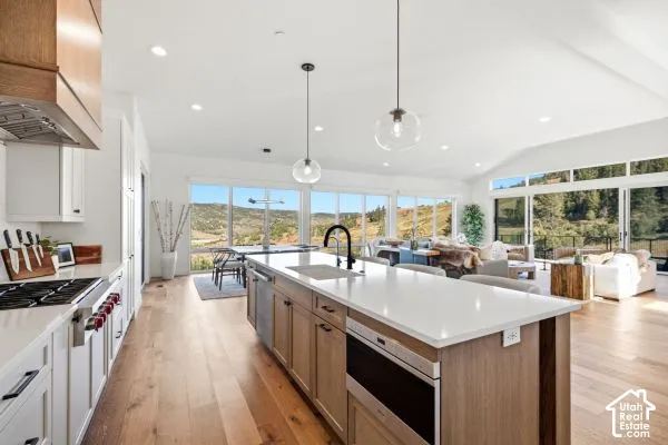 Open concept kitchen with a central island, recessed lighting, wood-finish flooring, and expansive windows. The photos are renderings only - these photos are for a similar unit in Discovery Ridge. Not this actual model.