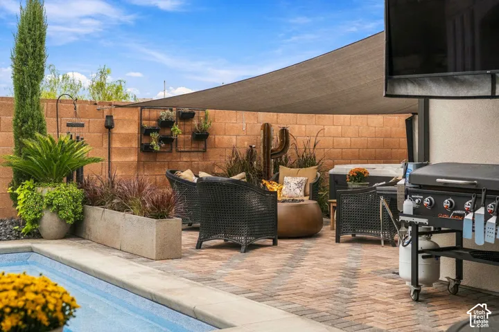 Expansive outdoor area featuring a swimming pool, brick paver patio, shade sail, built-in planter boxes, and a block wall perimeter