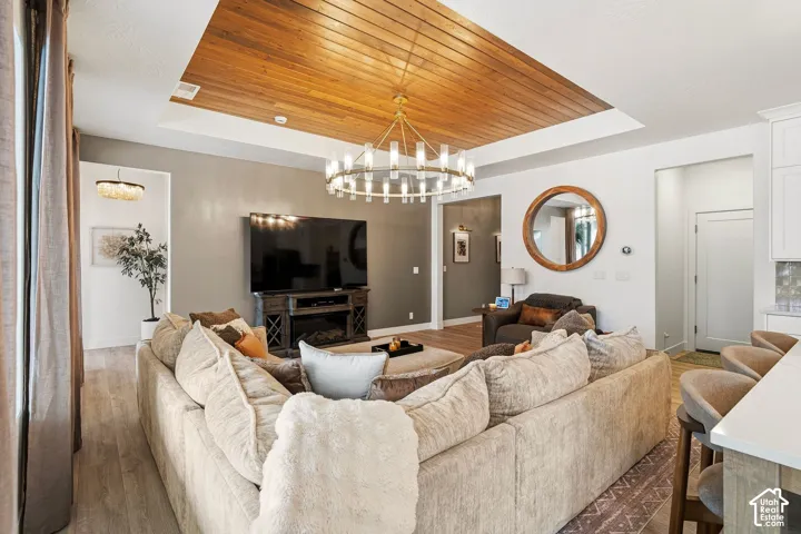 Wood-finish plank flooring throughout, vaulted ceiling with wood paneling, and an integrated electric fireplace