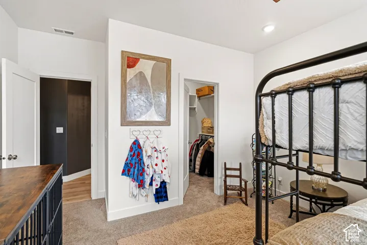 Recessed lighting illuminates the space, which includes a closet with built-in shelving, white trim, and neutral carpeting