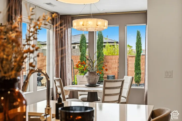 Dining area with a drum chandelier, large windows, and a built-in kitchen island featuring a gooseneck faucet
