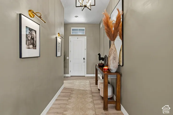 White paneled door with transom window, wood-finish flooring, recessed lighting, and wall-mounted light fixtures