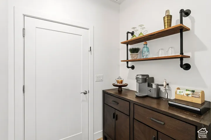 Built-in cabinetry with dark wood finish, wall-mounted shelving with wood-finish planks, and a solid white door