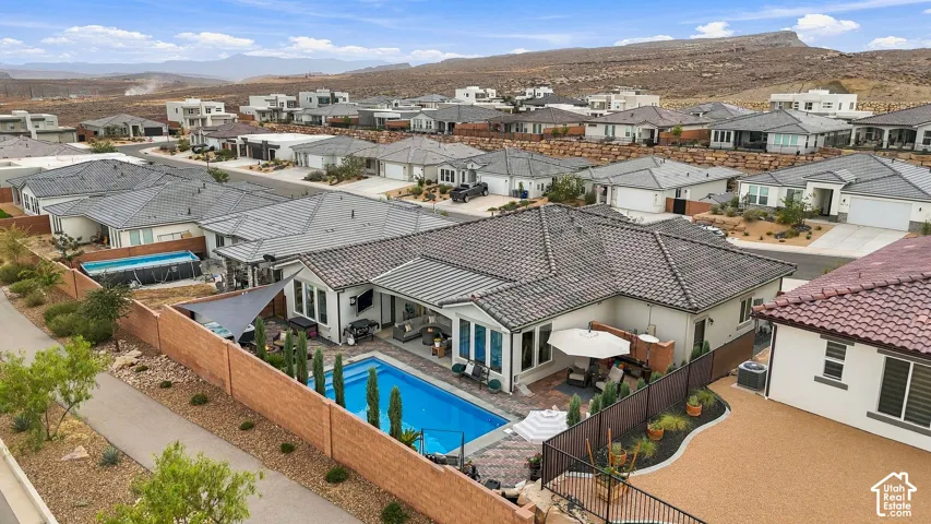 Modern residence featuring a rectangular swimming pool, an expansive paved patio area, and a tiled roof