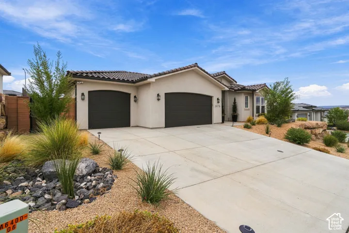 Stucco exterior with a tile roof, two-car garage with arched doors, and a concrete driveway