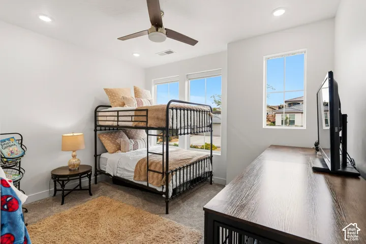 Recessed lighting, ceiling fan, and multiple windows illuminate this carpeted room