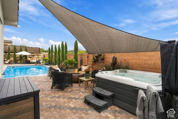 Swimming pool with a paved surround, shade sail, and a built-in spa