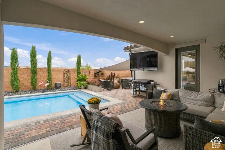 Covered patio featuring an outdoor pool, paver hardscaping, built-in fire pit, and recessed lighting