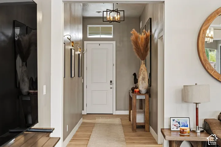 Foyer featuring wood-finish flooring, a white paneled door, and an overhead geometric light fixture