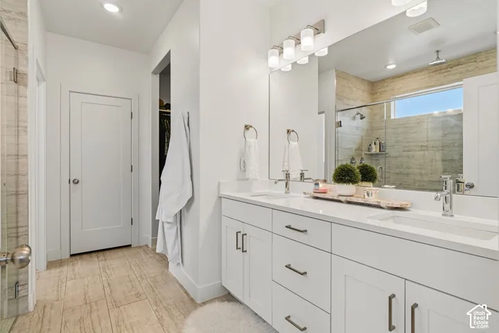Dual vanity with white cabinetry, polished chrome fixtures, and a large mirror