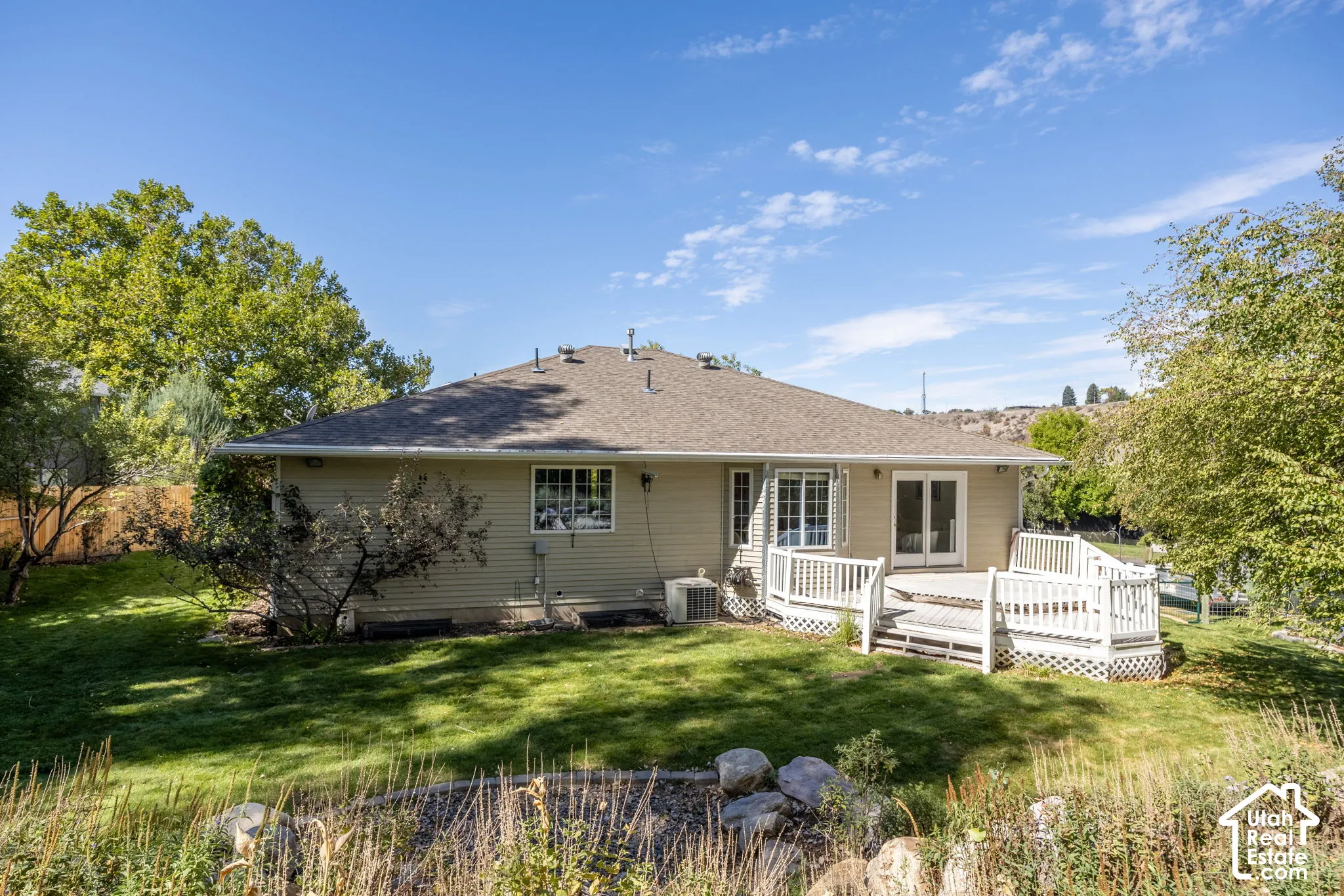 Expansive backyard with a manicured lawn, a multi-level deck, and mature trees