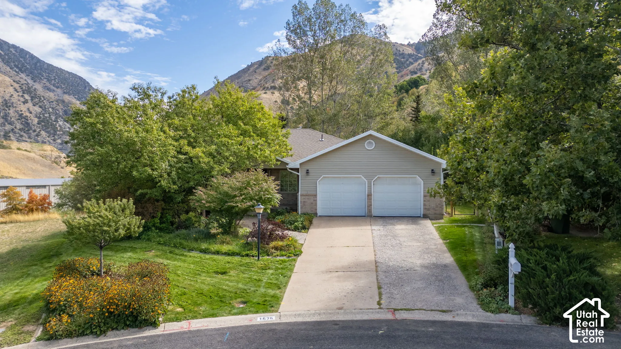 Single-story residence featuring a two-car garage, concrete driveway, and established landscaping