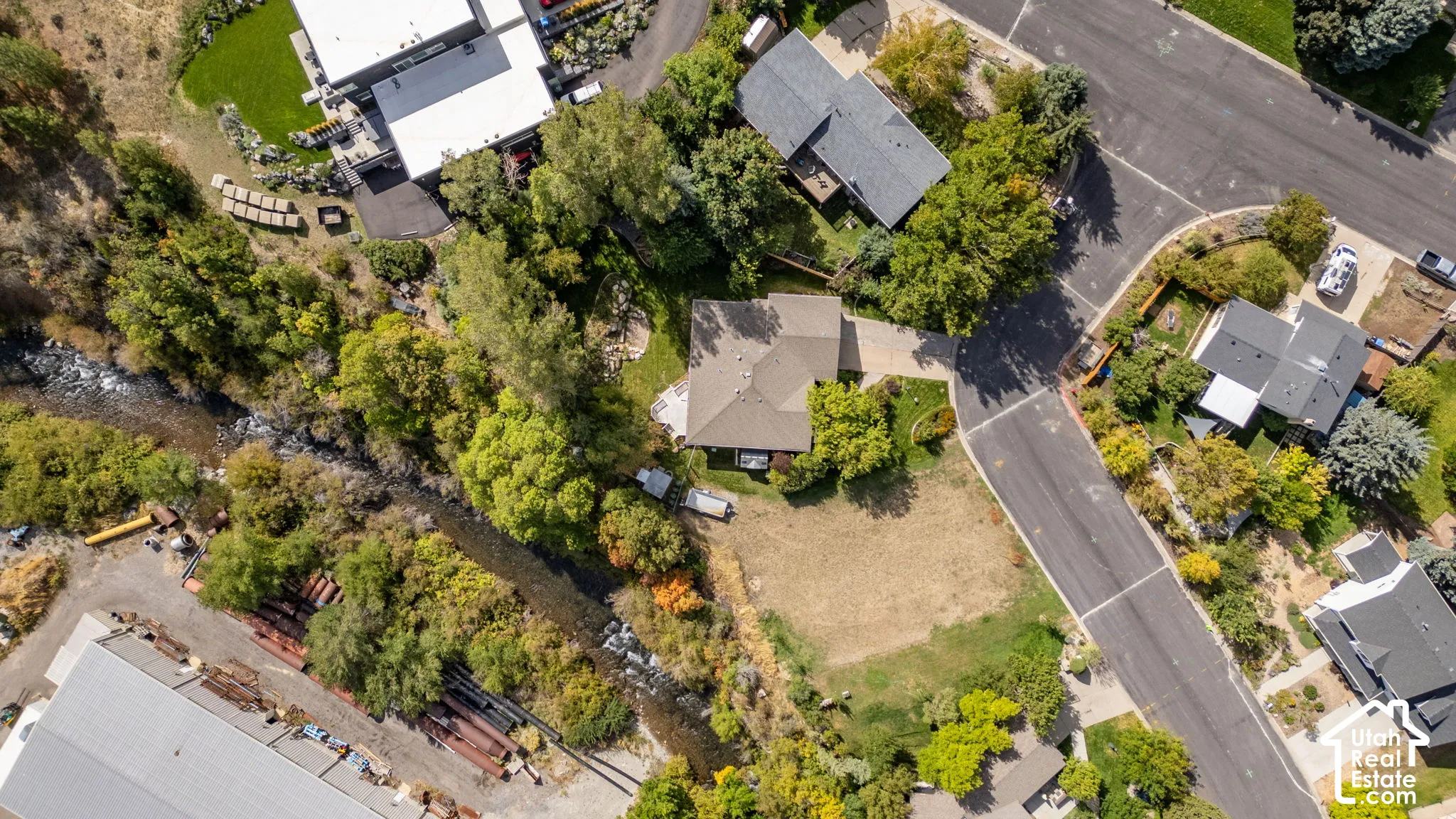 Aerial perspective showcasing a residential property with a natural water feature, surrounded by mature trees