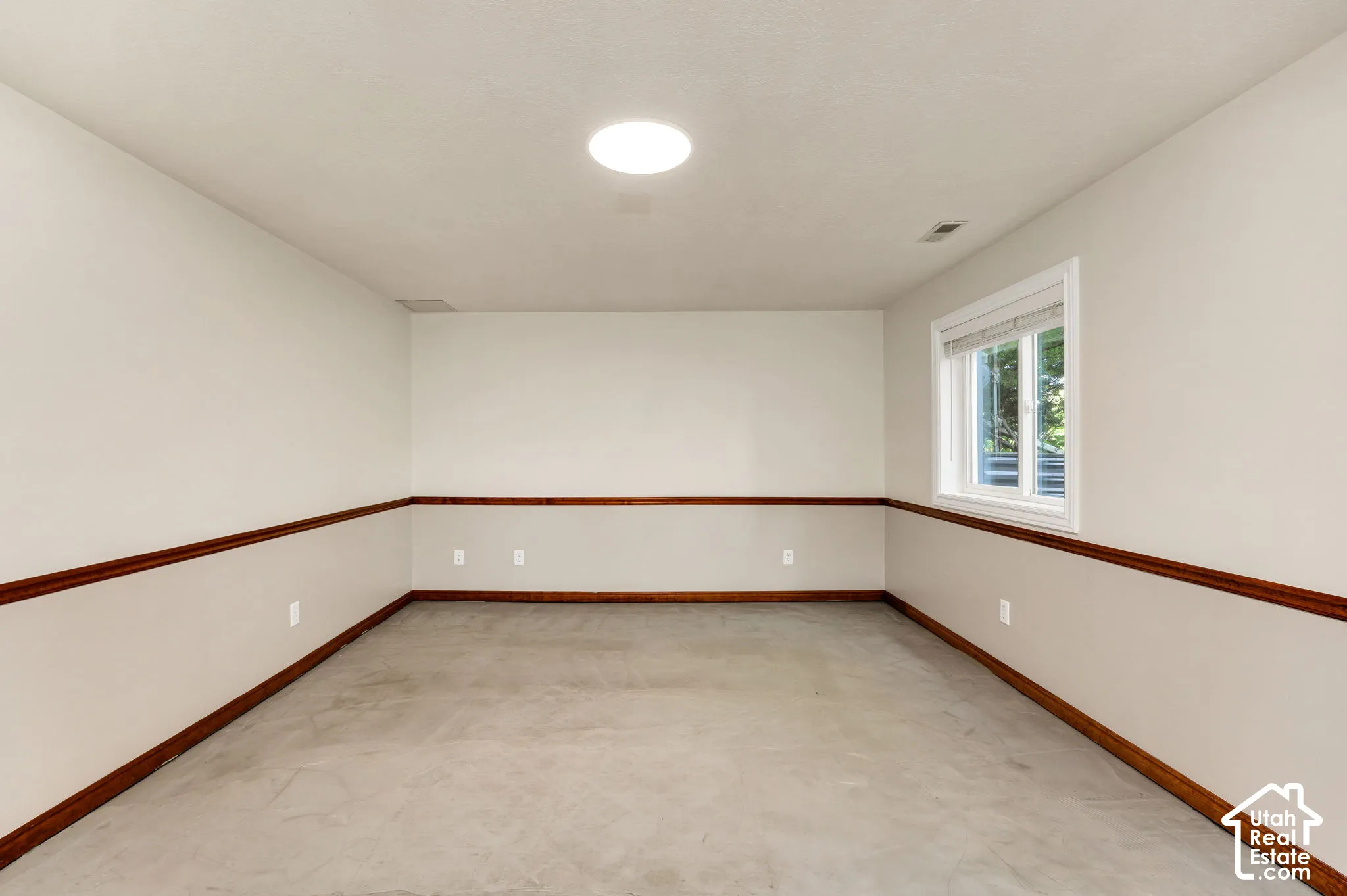 Recessed lighting, wood-finish chair rail, concrete floor, and a window for natural light