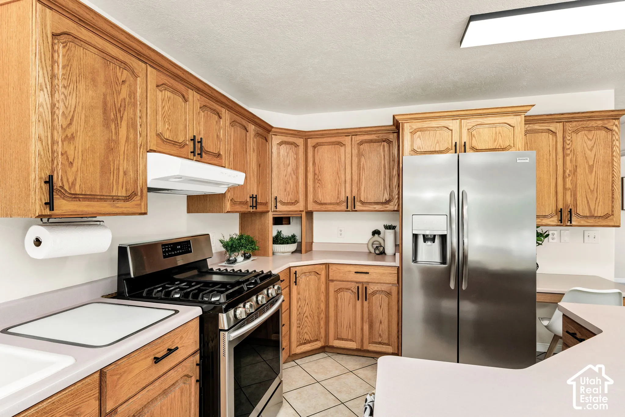 Kitchen featuring wood-finish cabinetry, stainless steel appliances, and tile flooring