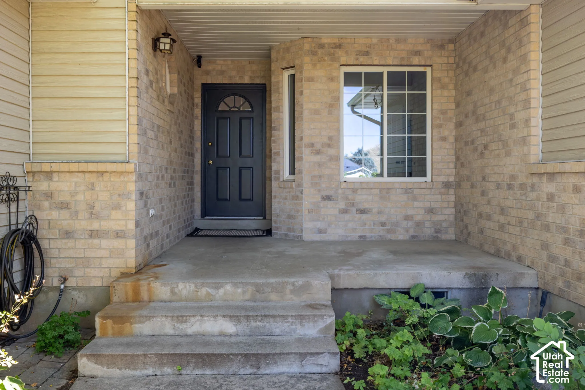 Brick facade with siding accents, covered entry, solid panel door with arched glass, and a multi-pane window