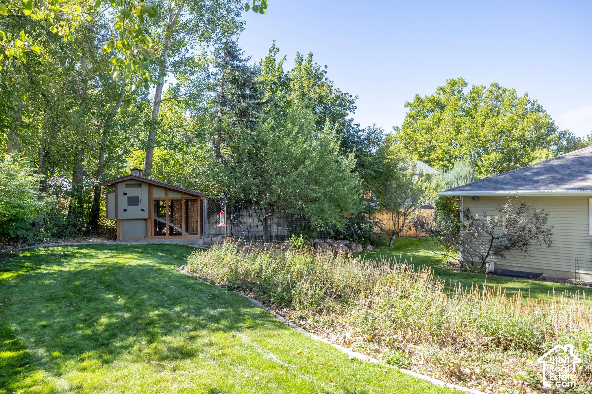 Expansive backyard featuring a manicured lawn, established trees, and a dedicated garden area