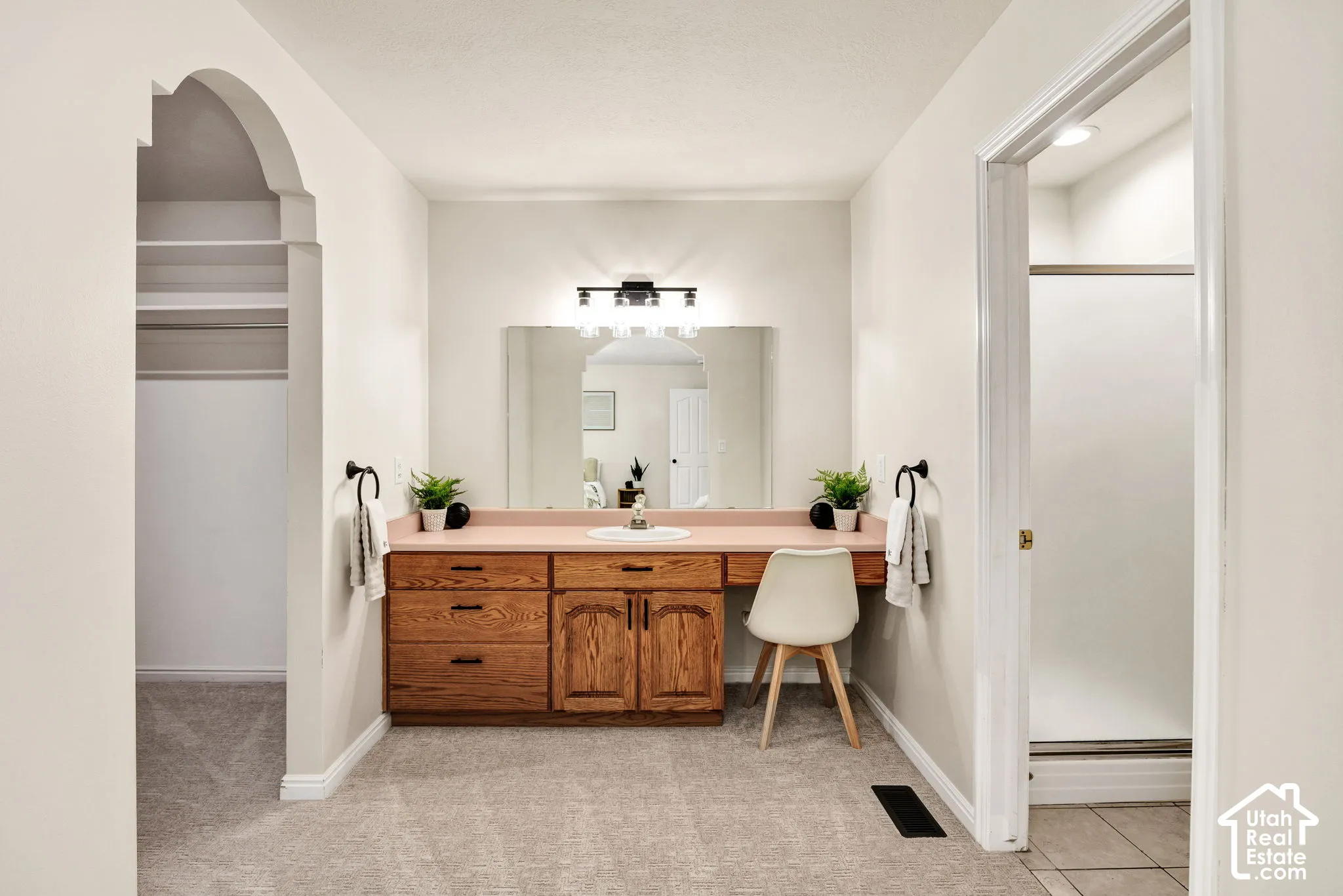 Wood vanity with a pink countertop, a large mirror, and a black vanity light fixture