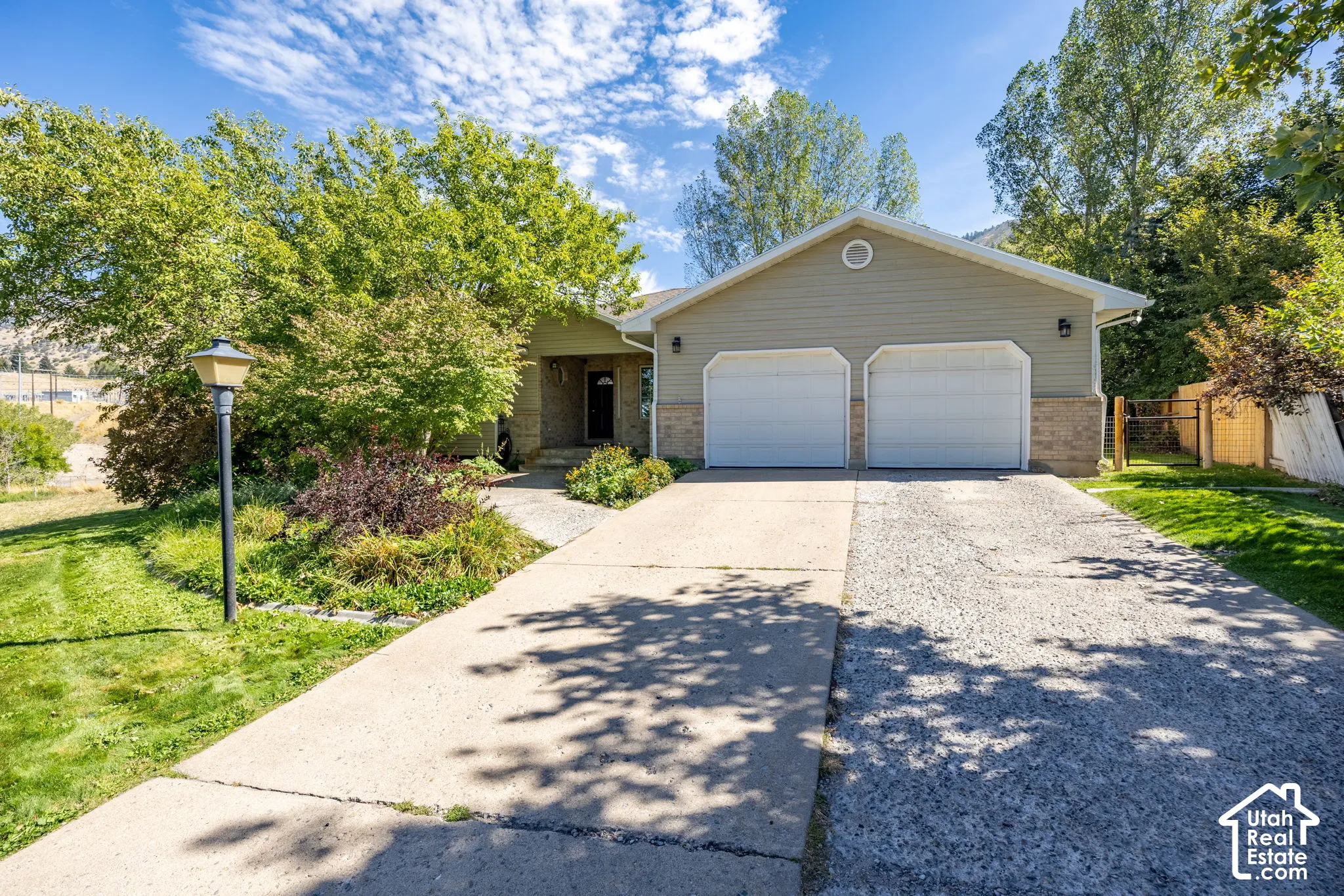 Exterior featuring a two-car garage, established landscaping, and a concrete driveway