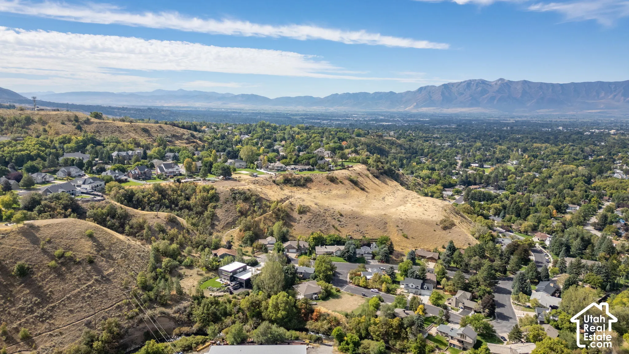 Mountainous backdrop, residential neighborhood, lush green landscaping, clear skies