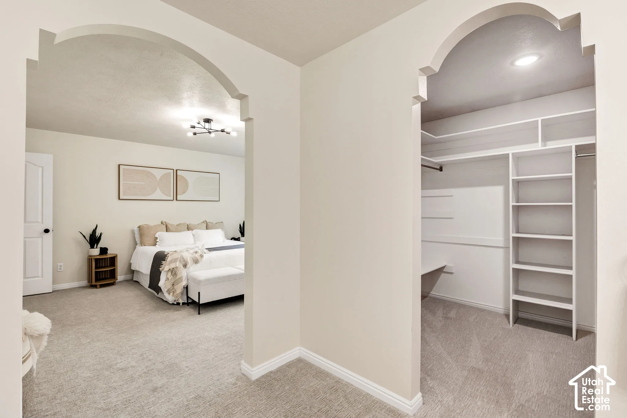 Archway entry to a bedroom with neutral wall tones and a contemporary ceiling light fixture