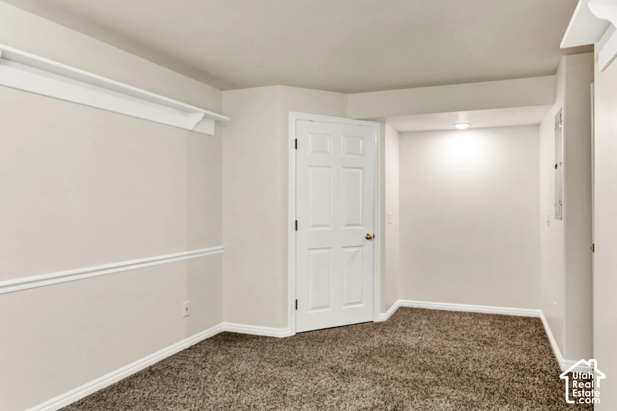 Plush carpet flooring, neutral wall paint, white trim, and a six-panel interior door
