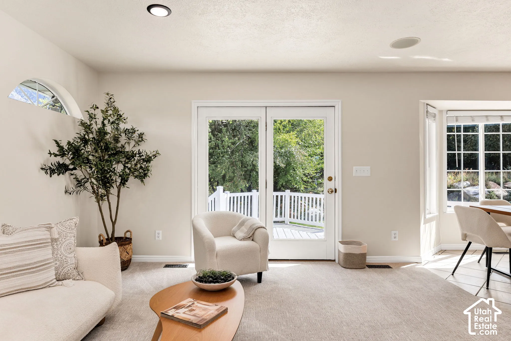 Recessed lighting, arched accent window, double glass doors, white deck railing, and a bay window with natural light