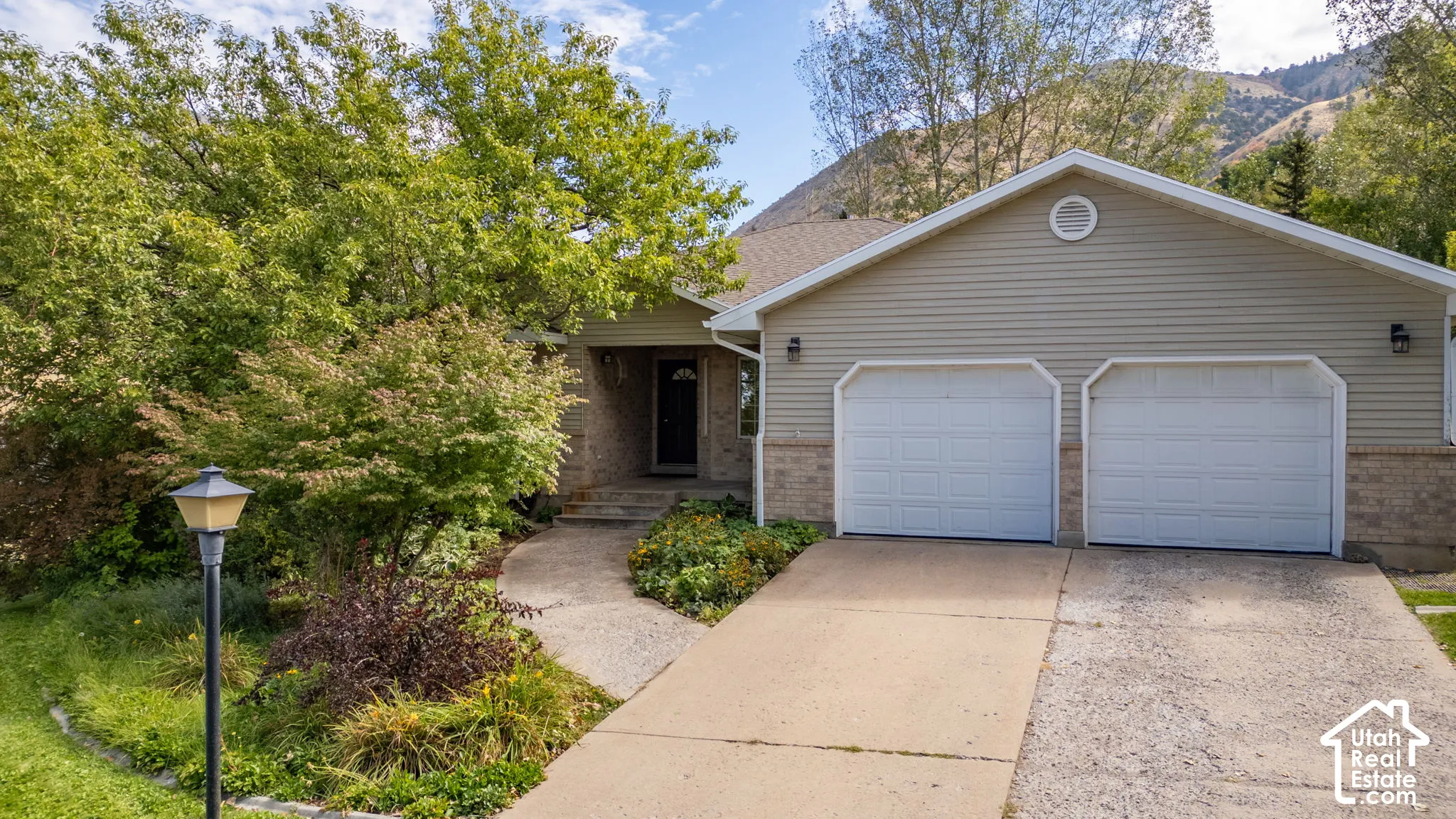 Two-car garage with panel doors, asphalt driveway, and mountain backdrop
