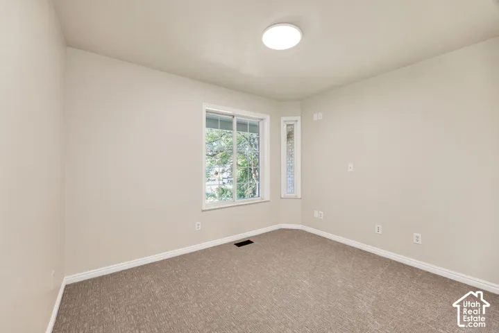 Neutral tone wall paint, textured carpeting, contemporary flush mount ceiling light, and window with natural light