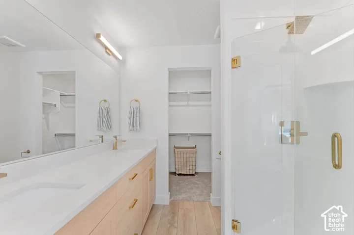 Dual vanity with light wood-finish cabinetry, white countertop, and gold-finish hardware