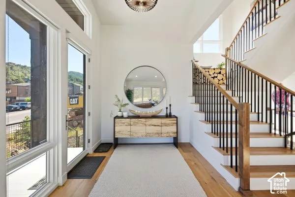 Entryway featuring wood-finish flooring, a modern staircase with wood handrails and black balusters, a built-in wood storage nook, and expansive windows. The photos are renderings only - these photos are for a similar unit in Discovery Ridge. Not this act
