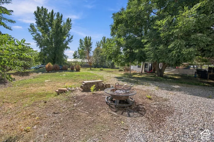 Expansive outdoor space featuring a gravel area, mature trees, and a fire pit