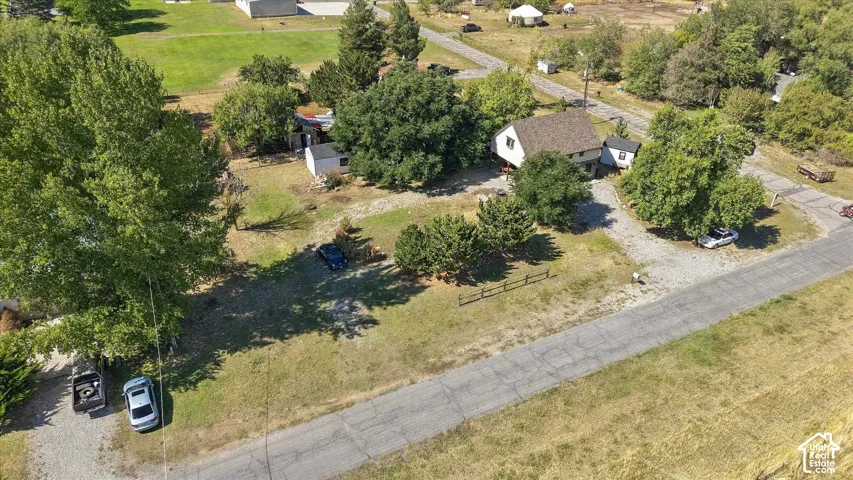 Property featuring a main residence, detached outbuilding, mature trees, and a gravel driveway