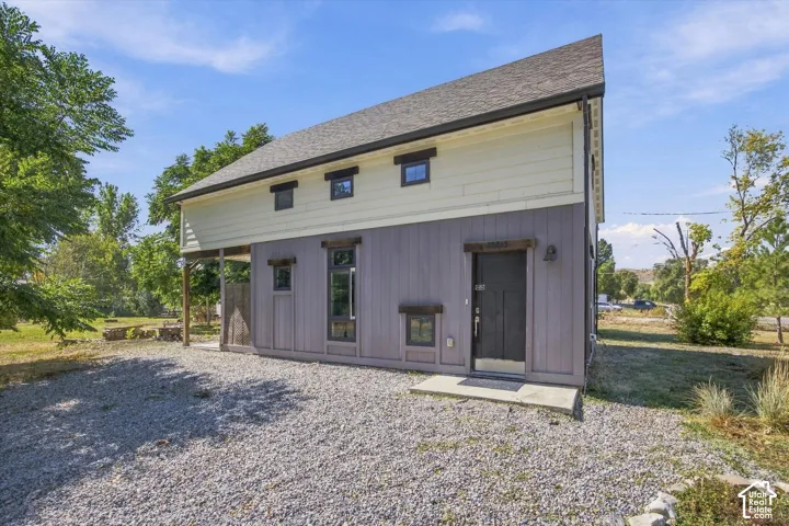 Two-story exterior with a sloped roofline, gravel ground cover, and a dark front door