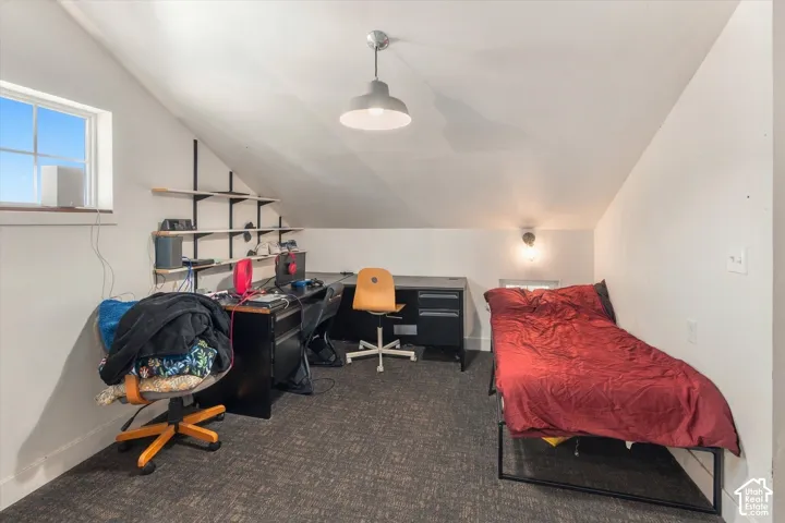 Sloped ceiling room featuring a window, textured carpeting, and built-in wall shelving