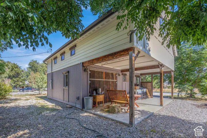Elevated structure featuring horizontal siding, a covered concrete patio, and exposed wood beams