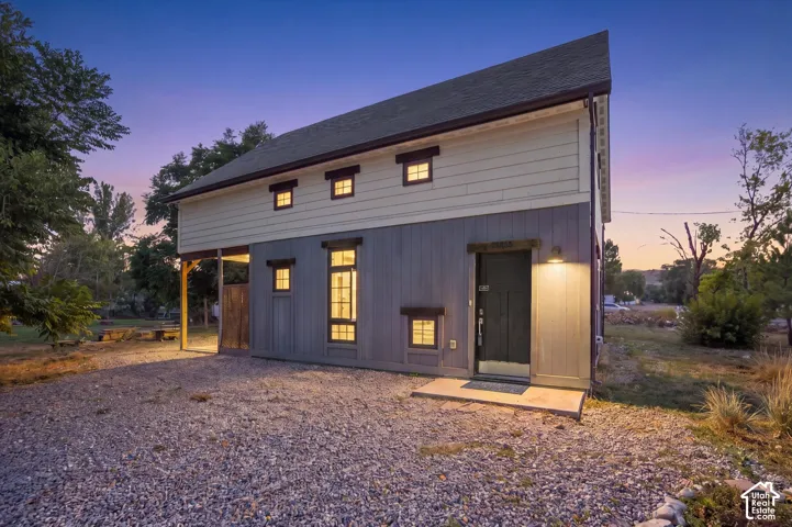Two-tone exterior with vertical and horizontal siding, multiple window styles, recessed entryway with sconce lighting, and a sloped roofline