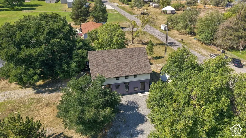 Two-story structure with a brown shingle roof, light-colored upper siding, and a darker lower facade